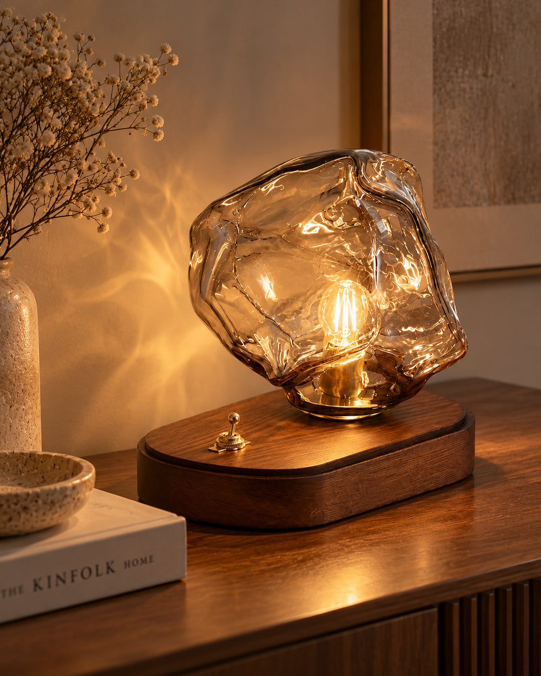 Ice rock glass table lamp glowing with a warm filament on a walnut base in a cosy living room