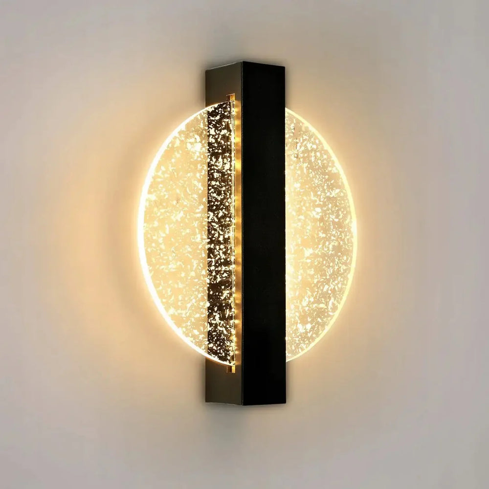 Luminous Halo round LED wall light glowing warm on a pale wall, black vertical bar over a glittering disc