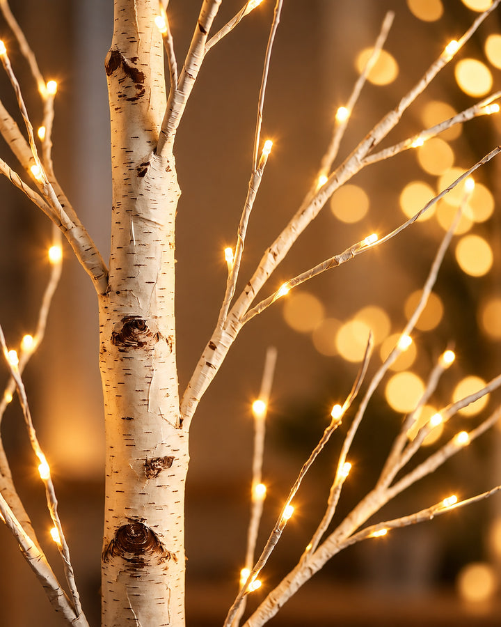 Close-up of the white birch bark trunk with tiny warm white LED lights glowing on the branches