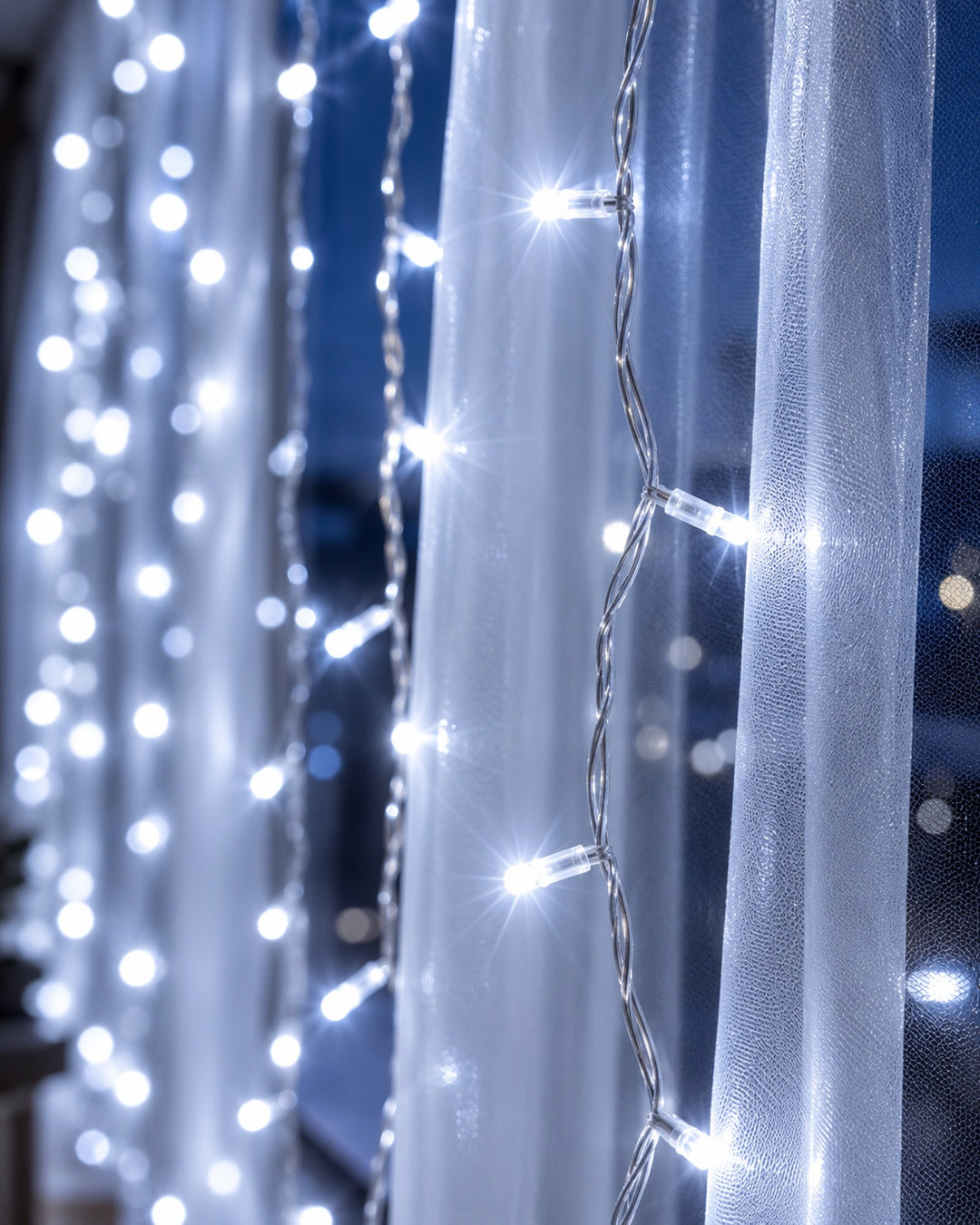 Close-up of cool white LED fairy curtain light strands behind a sheer curtain