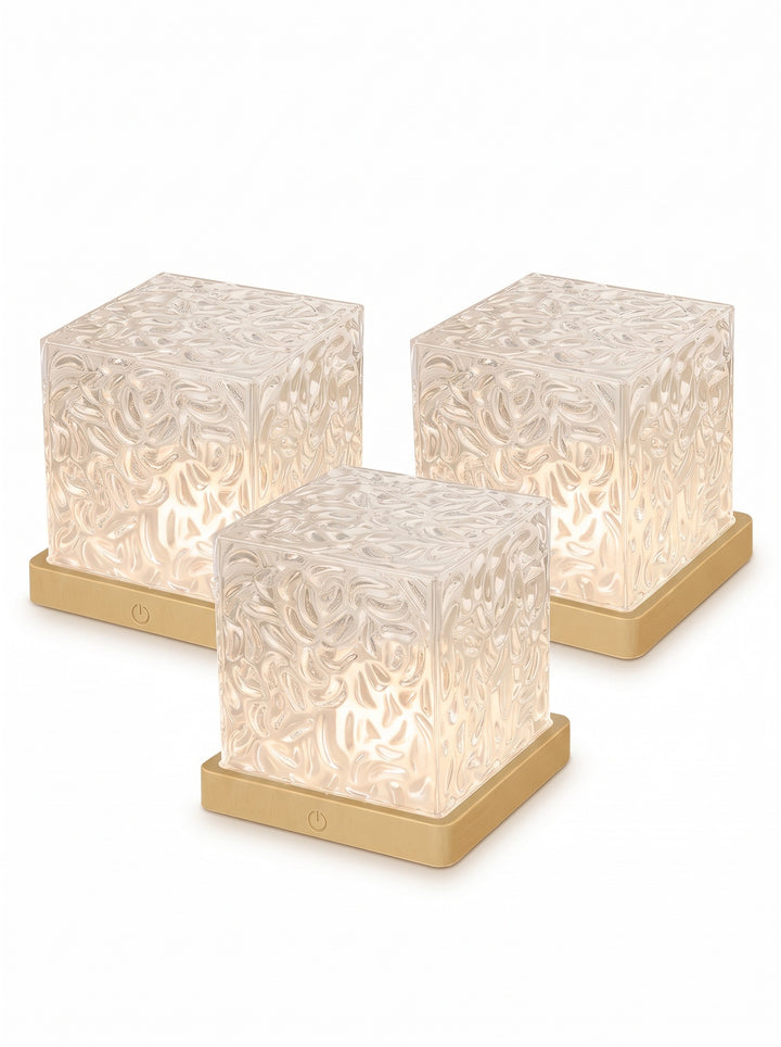 Three crystal cube lamps with faceted shades and wood-tone bases on a white background