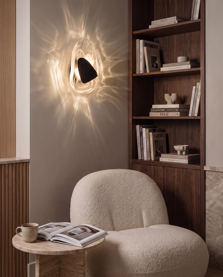 Black Ripple wall light casting rippling light above a bouclé lounge chair