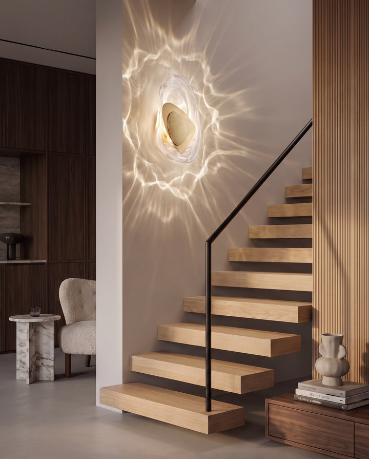 Gold Ripple wall light casting rippling reflections beside a modern floating staircase