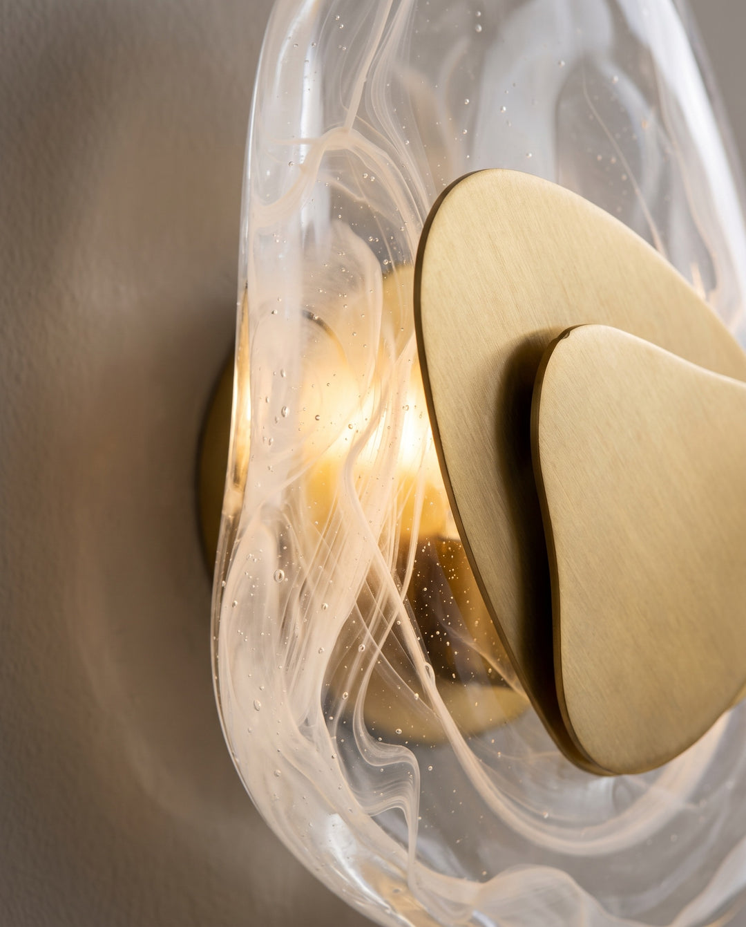Close-up of the swirled glass and brushed gold plate of the Ripple wall light