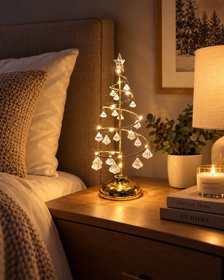 Gold-tone spiral Christmas tree light glowing on a bedside table at night
