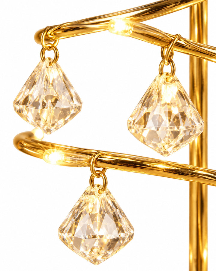 Close-up of the gold-tone spiral and clear faceted drops glowing warm white
