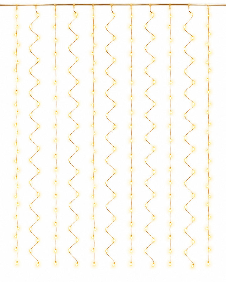 Copper wire curtain lights with strands hanging straight, glowing warm white on a white background