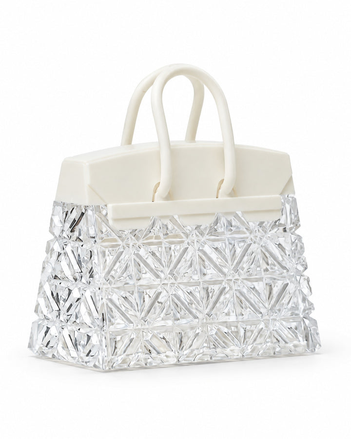 Handbag-shaped night light with a faceted clear body and white handles, switched off, on a white background
