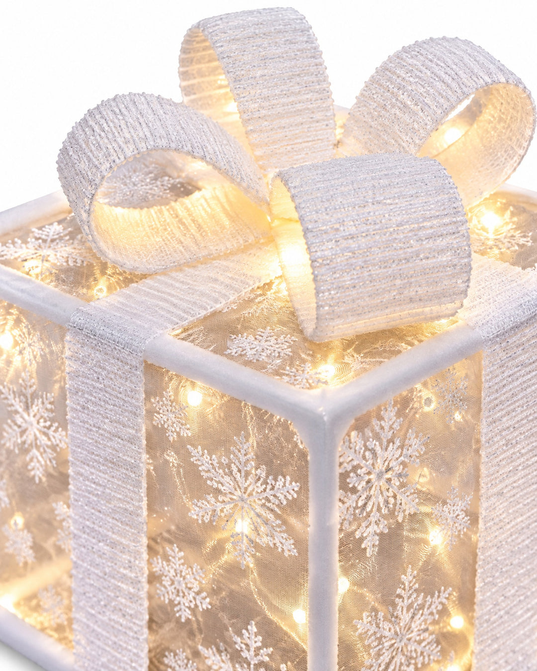 Close-up of a white bow and the snowflake pattern of a lit gift box