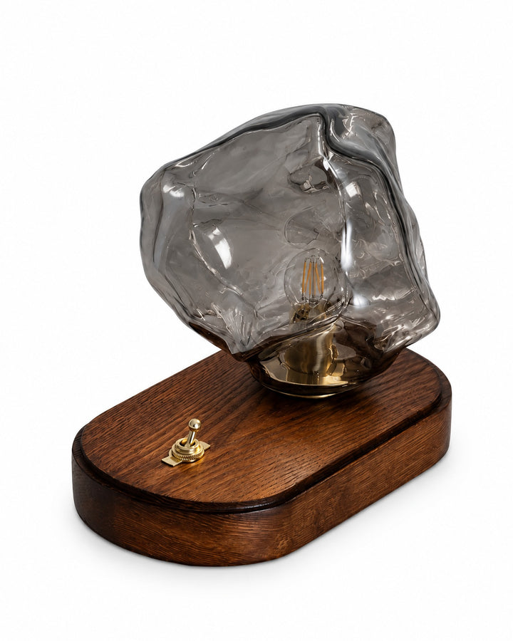 Ice rock glass table lamp with a grey shade and a dark oval base on a white background