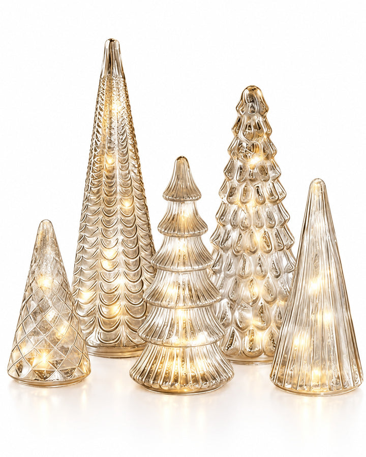 Set of five lit silver mercury glass Christmas trees of different shapes on a white background