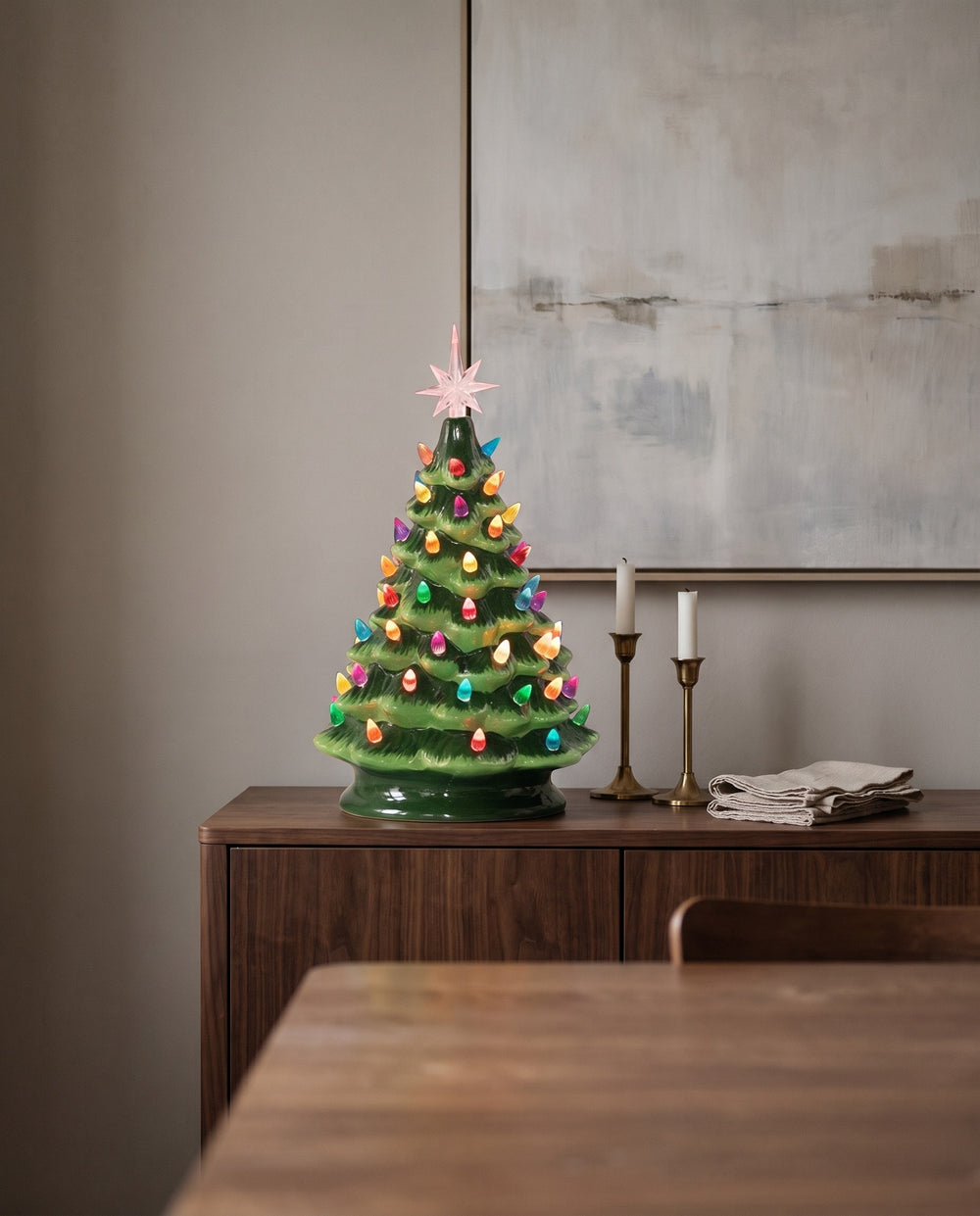 Glazed green ceramic Christmas tree glowing on a walnut sideboard in a modern dining room