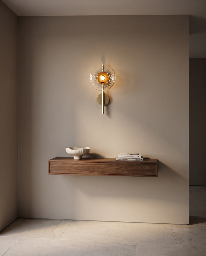 Orbe single head wall sconce in gold with amber glass above a floating walnut console