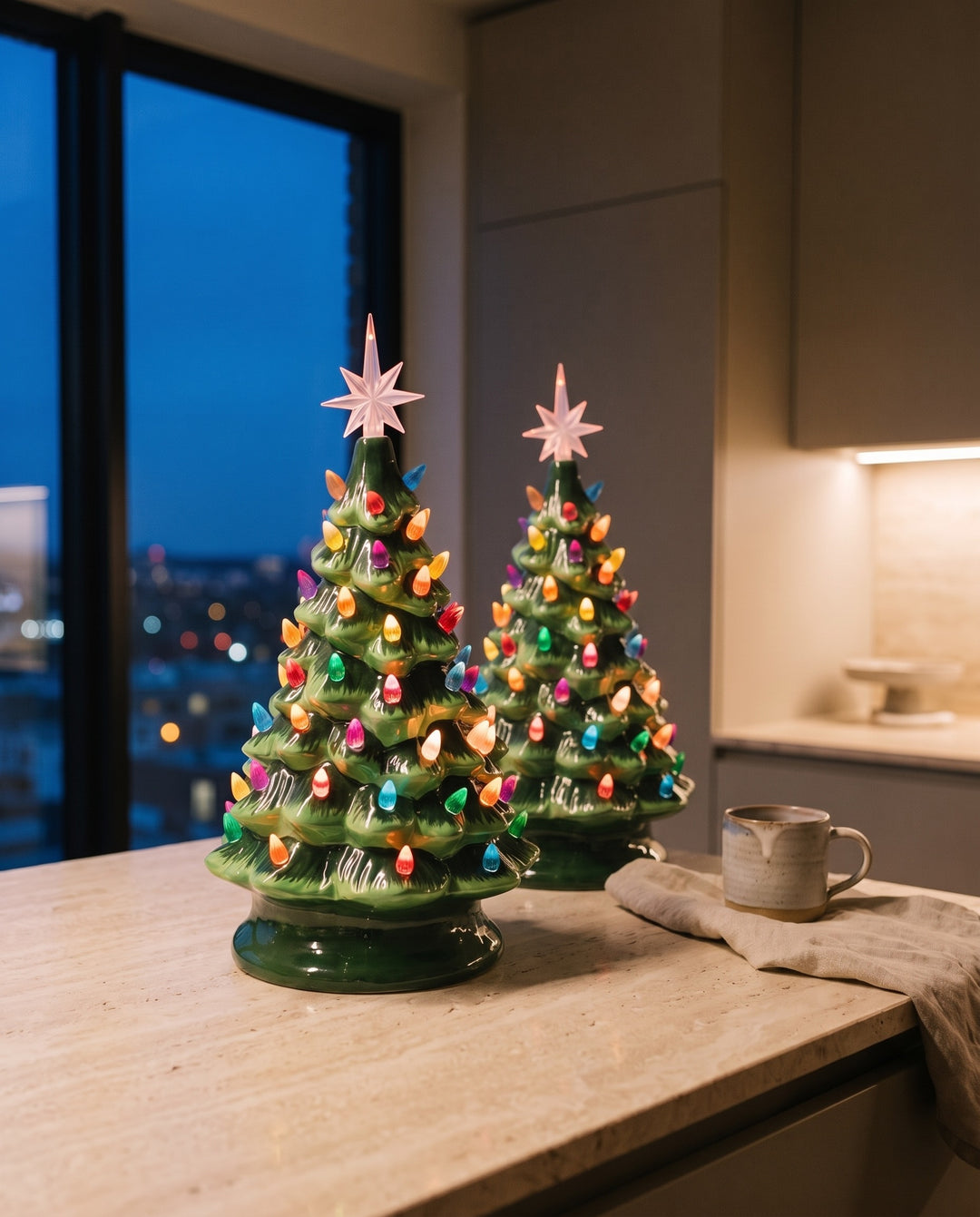 Two lit vintage green ceramic Christmas trees on a travertine kitchen worktop