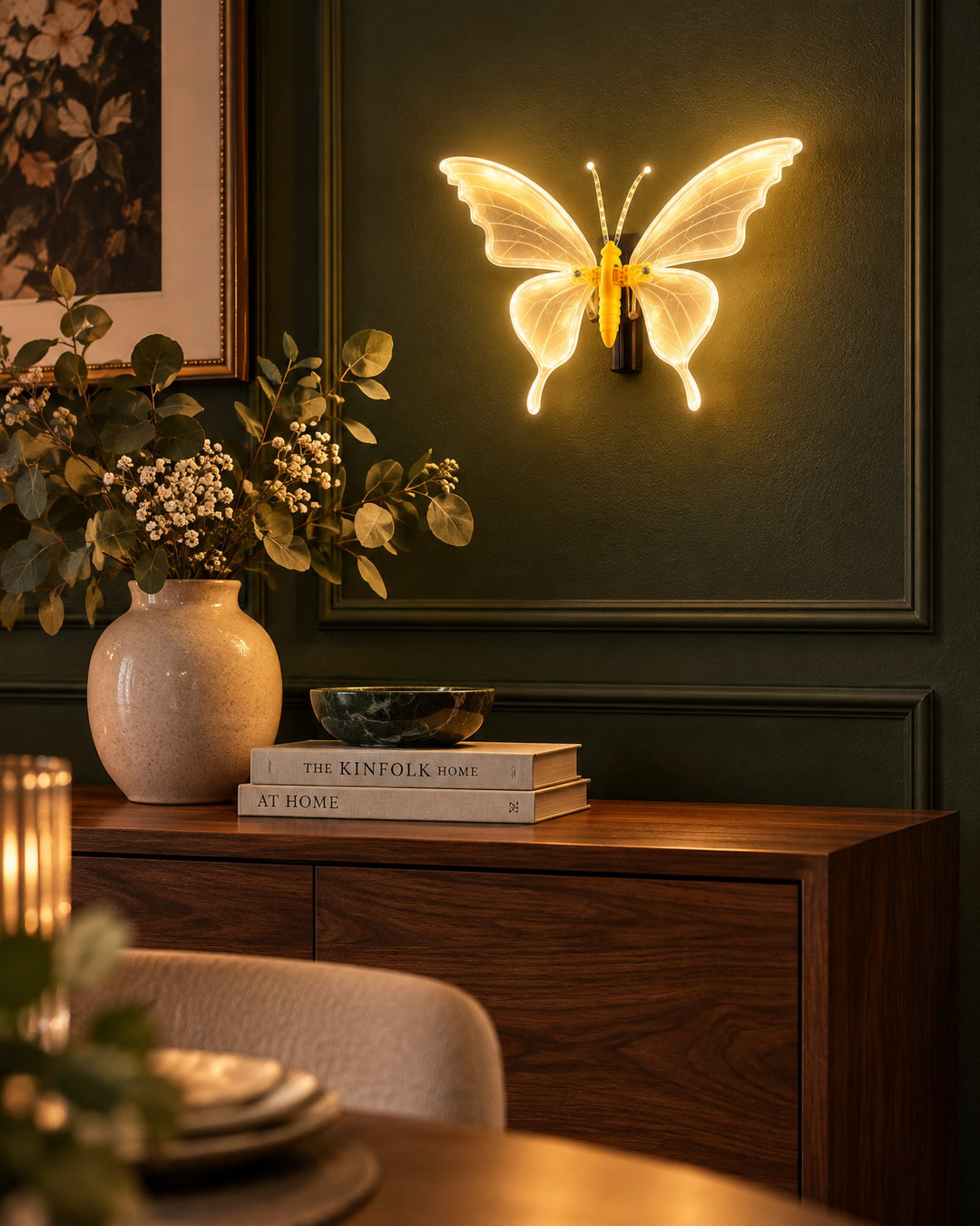 Glowing LED butterfly on a dark green dining room wall above a walnut sideboard