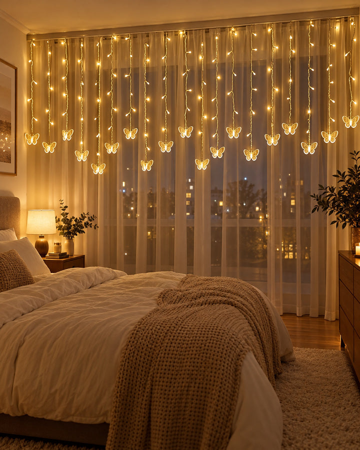 Butterfly curtain lights glowing in front of sheer white curtains in a bedroom at night