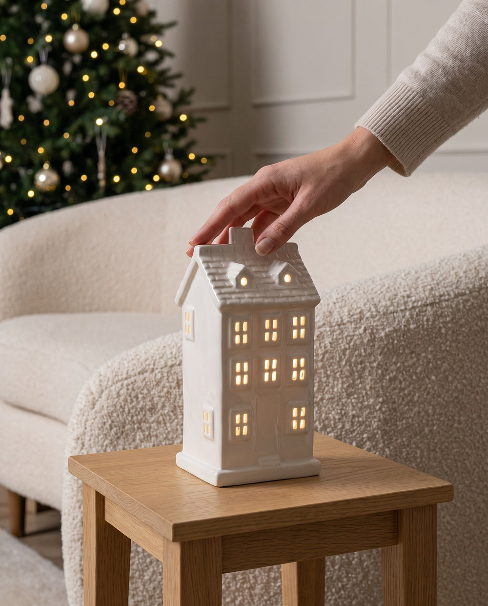 Hand setting the lit white ceramic Villa house on a small oak side table