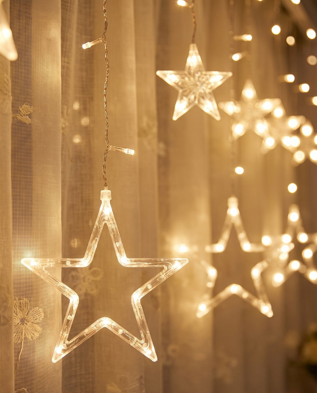 Close-up of warm white LED stars in front of sheer linen curtains