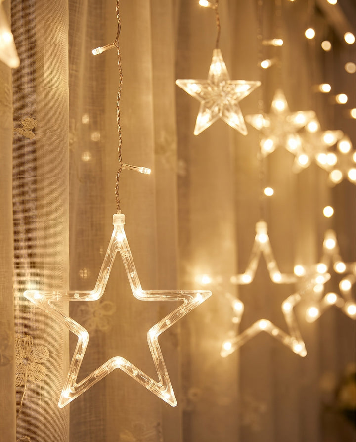 Close-up of warm white LED stars in front of sheer linen curtains