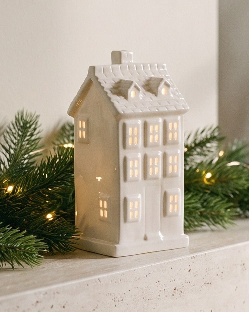 Close-up of the white ceramic Villa house with dormer windows, its windows glowing warm
