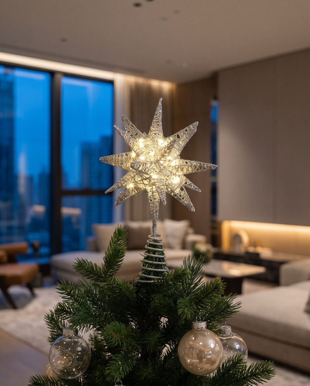 Silver glitter 3D star tree topper lit on top of a Christmas tree in a modern living room