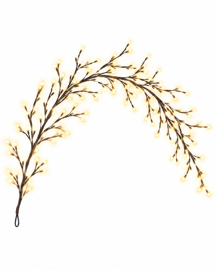 Flexible willow vine light bent into a soft arch, lit warm white, on a white background
