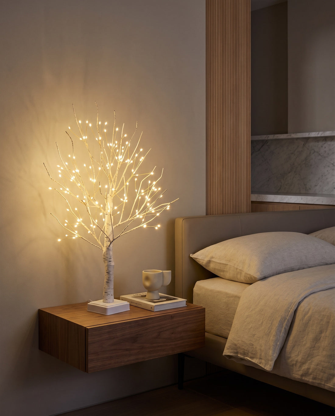 Birch tree lamp glowing on a floating bedside table in a modern bedroom
