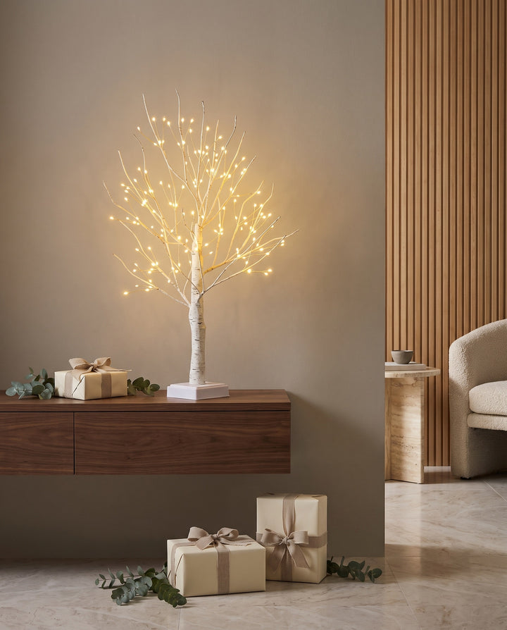 Birch tree lamp on an entryway console with wrapped Christmas gifts