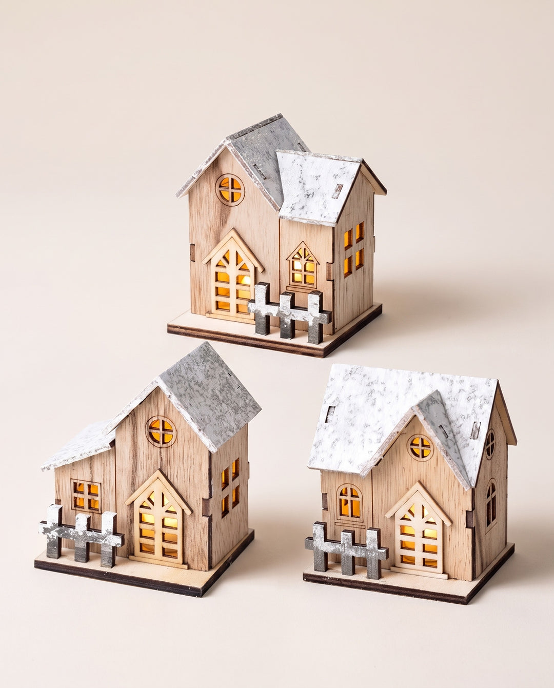 Three wooden LED houses with snowy roofs and glowing windows