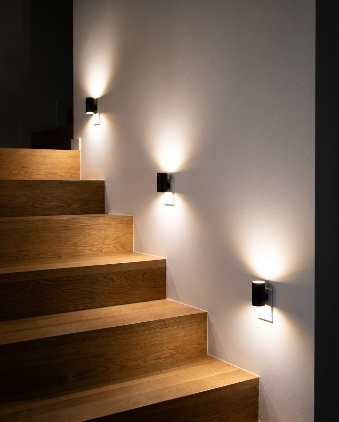 Three plug-in night lights lighting a staircase at night