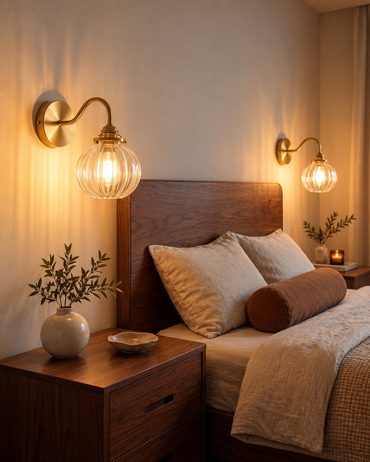 Pair of ribbed glass globe wall sconces lit on either side of a bed