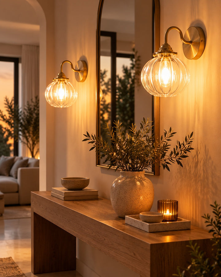 Two ribbed glass globe wall sconces framing an arched mirror above an entryway console