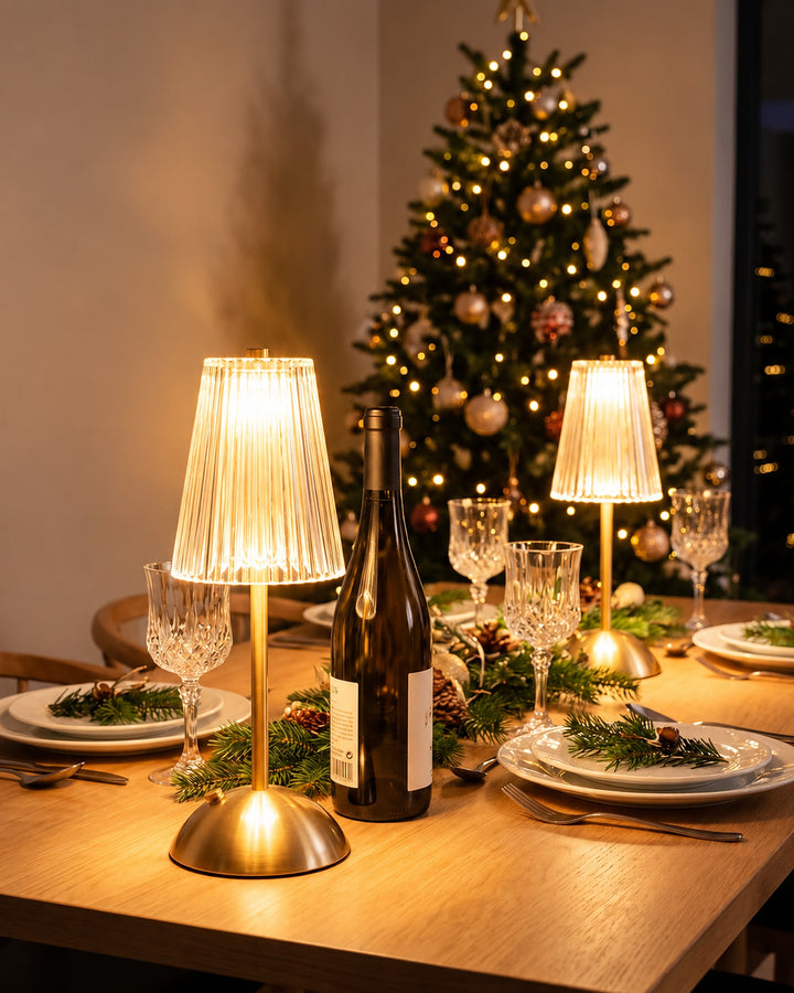 Two cordless ribbed table lamps lit on a Christmas dinner table next to a wine bottle