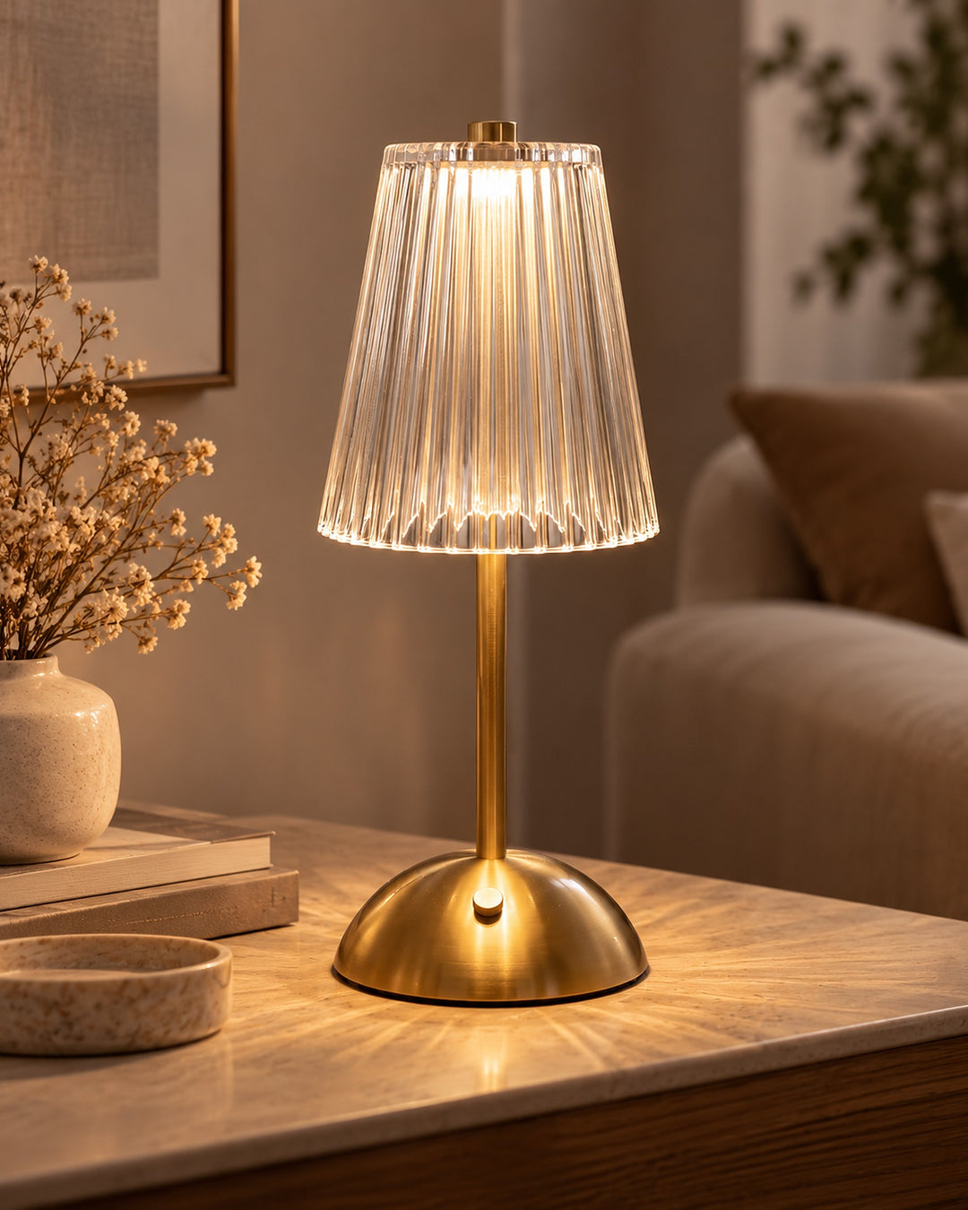 Cordless ribbed glass table lamp with a gold-tone base glowing on a living room side table