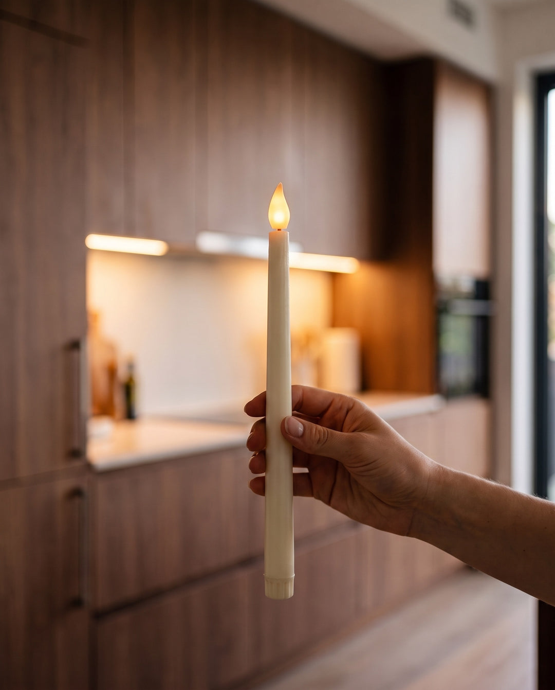 Hand holding one lit ivory flameless LED taper candle