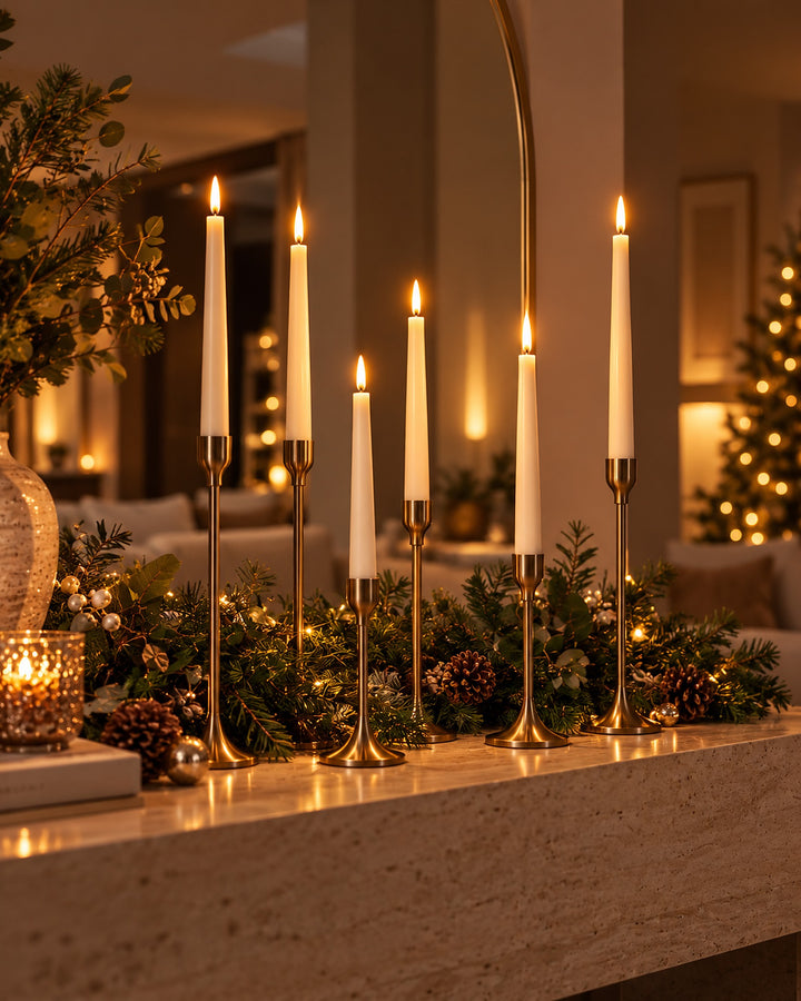 Six ivory flameless LED taper candles glowing in brass candlesticks on a festive console